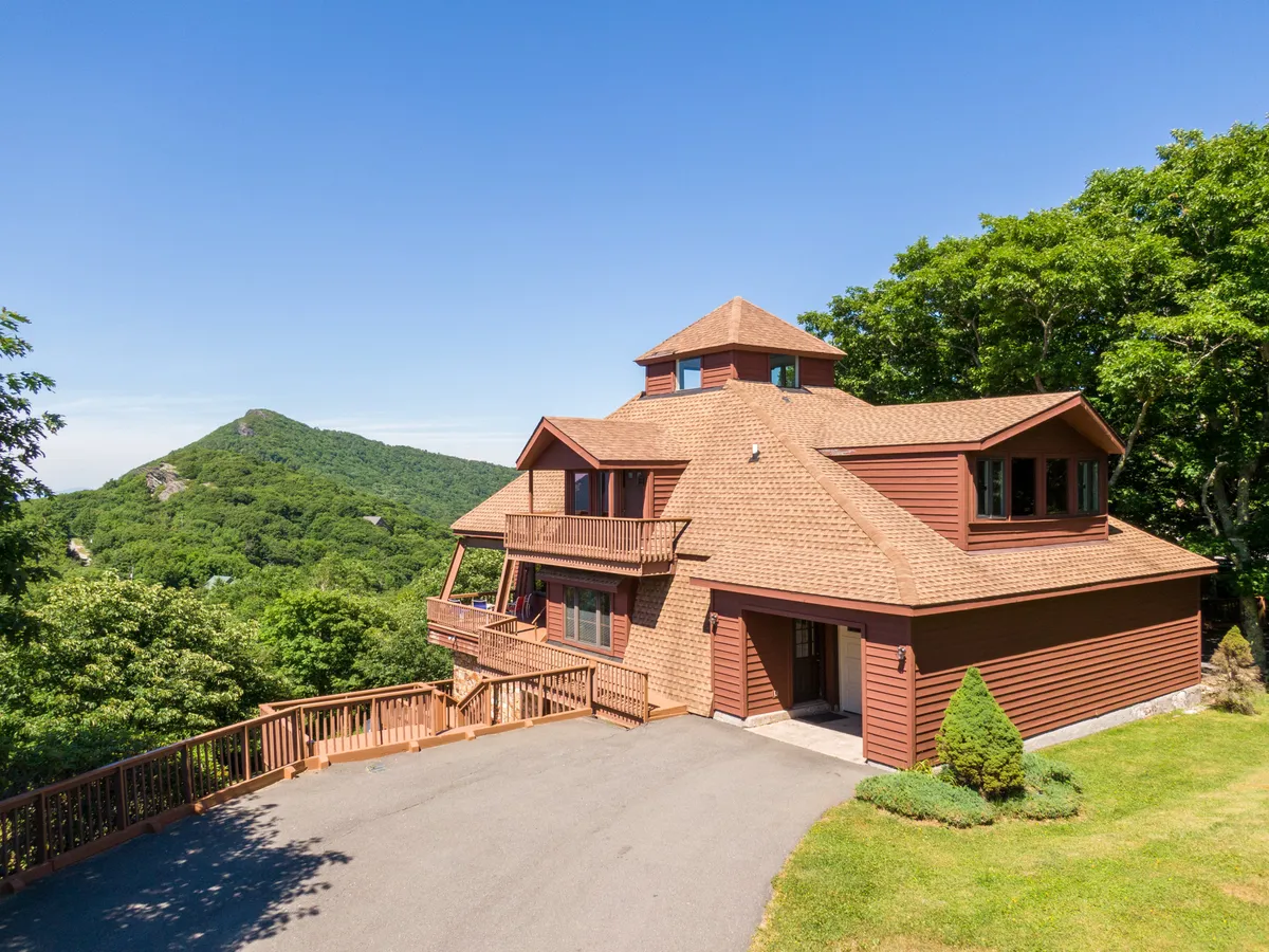 This image showcases the house set against a breathtaking mountain backdrop, surrounded by natural beauty. The deck and outdoor gathering spaces invite guests to step outside and take in the expansive views, emphasizing the property's direct connection to the outdoors and mountain adventures.